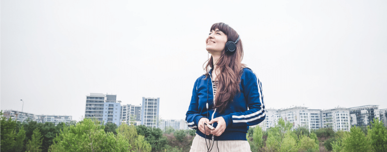 Woman in a city praying wth headphones on