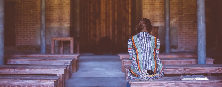 Woman praying by a church door